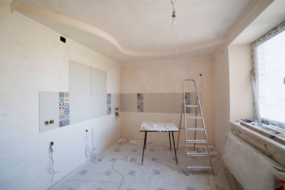 Kitchen mid-renovation with ladder and construction materials awaiting debris removal